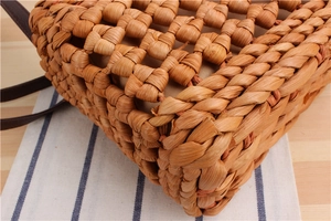Detailed view of handmade woven straw bag with checkered pattern and brown leather strap