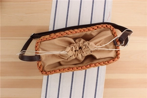 Detail of woven straw bag showing orange braided texture, drawstring liner and leather strap