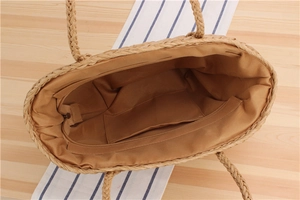 Detail view of woven straw tote bag interior with zipper pocket and brown fabric lining