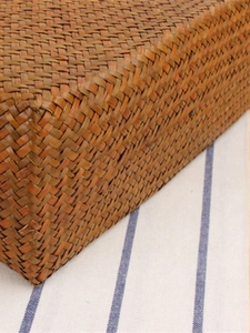 Handcrafted straw woven shoulder bag with vintage rustic texture on striped background