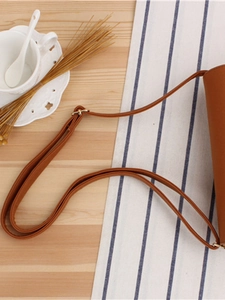 Brown PU leather woven shoulder bag with adjustable strap on a rustic wooden table