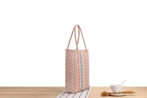 Detailed view of striped woven tote bag with pink and blue plastic braided handles