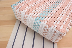 Detail of woven plastic shopping bag corner showing pink white and blue striped pattern