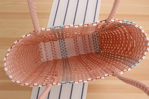 Top view of pink striped plastic woven tote showing spacious interior on a wooden table