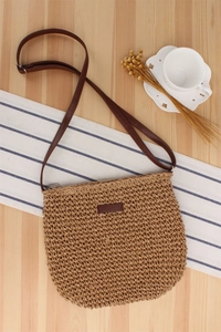 Detail of woven paper straw crossbody bag with brown leather strap and zip closure