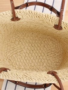 Large woven paper straw beach tote bag with brown leather handles on summer picnic background