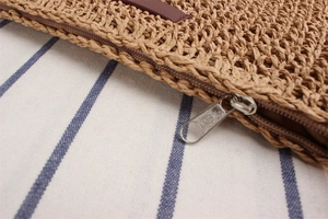 Close-up of small woven crossbody bag showing fiber texture and silver metal zipper
