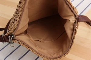 Macro view of woven straw bag interior with brown lining, pocket and zipper closure