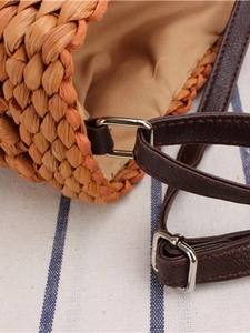 Handmade woven straw crossbody bag with brown leather strap and rustic texture