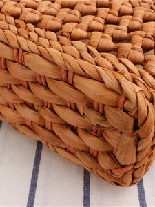 Detailed view of handmade woven straw crossbody bag featuring natural fiber textures