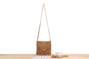 Detail einer handgewebten Makramee-Tasche im Boho-Stil mit geometrischem Muster und Fransen