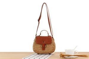 Detail of straw woven bag with brown leather strap on wooden table in a cafe setting