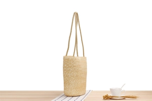 Detail of the natural straw woven bag texture with long cotton rope handles on a table