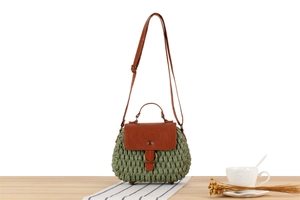 Detail of sage green straw woven bag with brown faux leather flap and vintage metal buckle