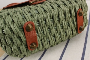 Detail of green woven handbag with brown leather base and vintage bronze rivets