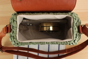 Interior view of green straw crossbody bag showing space for phone and cosmetics