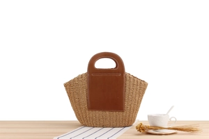 Close-up of large paper rope woven tote bag with brown leather patch on a wooden table