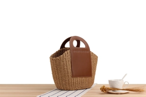 Detail of khaki paper rope woven tote bag with dark brown leather handle and rustic finish