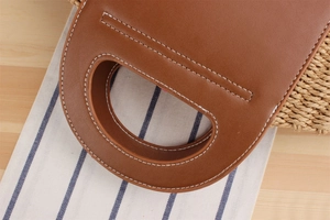Detailed close-up of brown PU leather handle with white stitching on woven tote bag