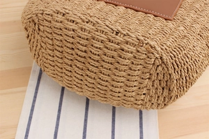 Detailed close-up of woven paper straw texture and stitched brown leather label on bag