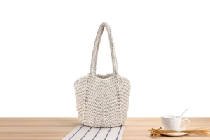 Detail of hand-woven beige cotton tote bag showing texture on a wooden table