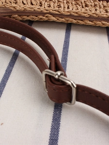 Straw woven crossbody bag with brown leather strap and adjustable silver metal buckle detail