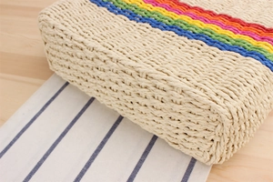 Detailed close-up of handmade rainbow striped straw bag with woven fiber texture