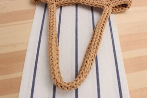 Detail of hand-woven cotton bucket bag handles showing fine khaki fiber texture
