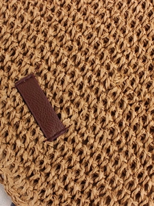 Straw woven crossbody bag with brown leather patch detail and natural texture