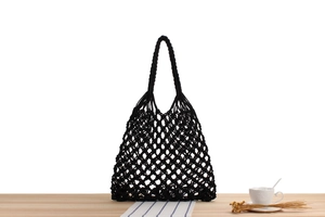 Detail of a black hand-woven mesh shoulder bag with a minimalist hollow diamond pattern