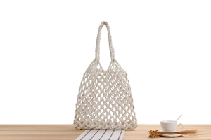 Detailed close-up of handmade white cotton woven mesh bag on a wooden surface