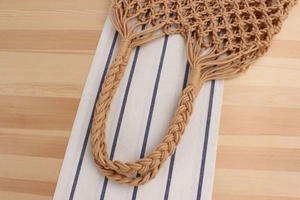 Close-up of thick braided handles on a beige woven mesh bag for a summer beach holiday