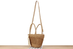 Détail de la texture du sac bandoulière en paille avec pompon et perle