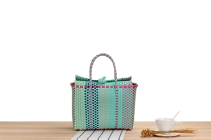 Detail of colorful hand-woven plastic tote bag featuring mint green and pink beach patterns