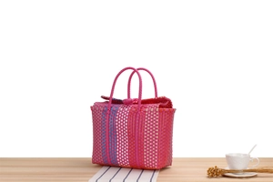 Detail of hand-woven plastic beach basket with colorful stripes and round double handles
