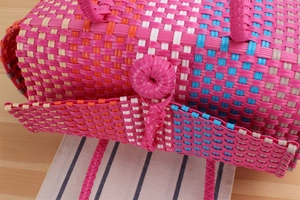 Detail of woven plastic beach bag featuring pink plaid pattern and round clasp closure