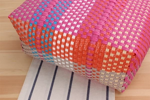 Detail of colorful hand-woven plastic picnic basket with vibrant grid texture and patterns