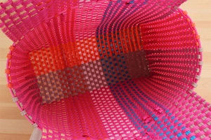 Top view detail of pink woven basket interior showing durable plastic weave and colorful stripes