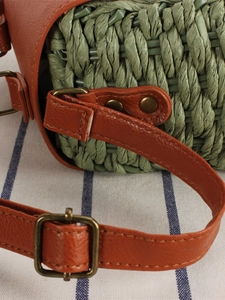 Minimalist green woven shoulder bag with brown leather strap and bronze metal hardware