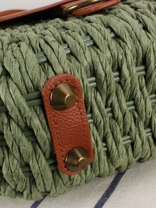 Vintage green woven straw bag with brown leather trim and retro metal rivets for beach vacation