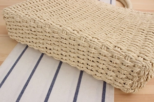 Détail rapproché d'un sac à main beige en paille tressée avec texture en fibres naturelles