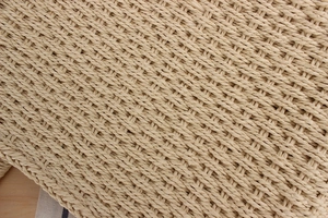 Gros plan sur la texture d'un sac à main en paille tressée avec fibres beiges