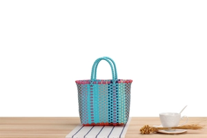 Detail of colorful woven tote bag with vibrant macaron straps on a rustic table