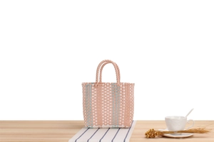 Close-up of pink and orange woven picnic basket on a wooden table with home decor