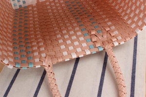 Detail of colorful woven picnic basket showing handle attachment and textured pattern