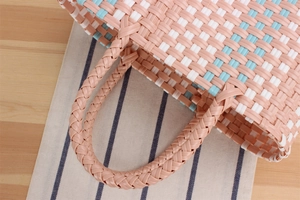 Detailed view of pink and blue woven plastic basket with sturdy multi-strand handles