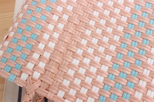 Close-up of pastel woven texture with pink, white and blue patterns on a picnic bag