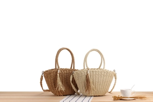 Detail of woven straw tote bags with elegant pearl charms and tassel accents