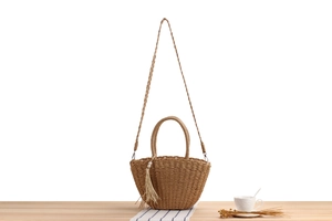 Detail of handmade woven straw crossbody bag with pearl tassels and wooden handles