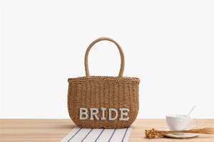 Close-up of woven paper straw handbag featuring pearl BRIDE lettering for weddings